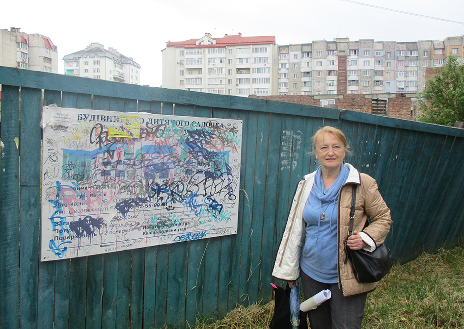  Тетяна Рашкевич біля залишків будівельної «візитівки» на огорожі довгобуду дошкільного навчального закладу.